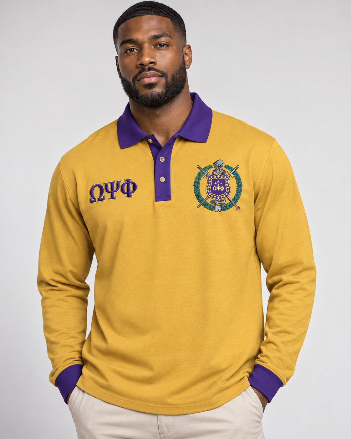 Omega Psi Phi man wearing old gold long-sleeve polo with purple collar, placket, cuffs, crest, and Greek letters