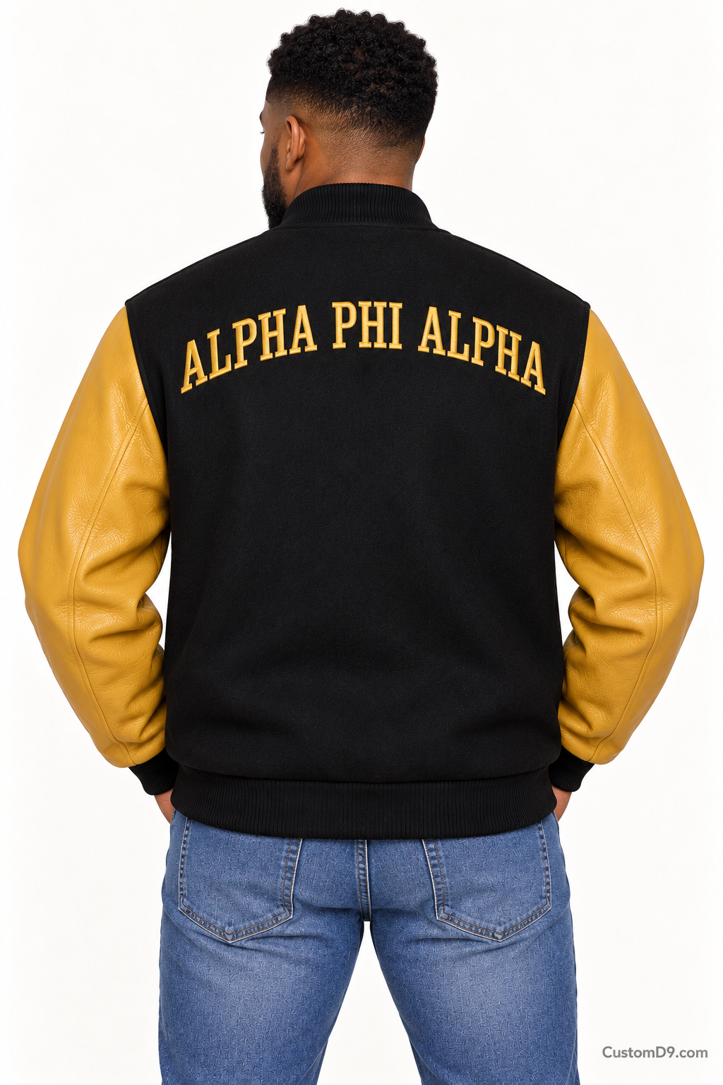 Black man modeling Alpha Phi Alpha premium contrast varsity jacket with black body and old gold sleeves, back view.