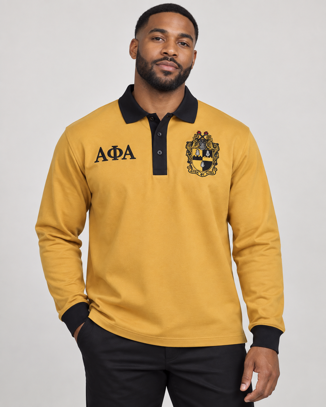 Alpha Phi Alpha man wearing old gold long-sleeve polo with black collar, placket, cuffs, crest, and Greek letters