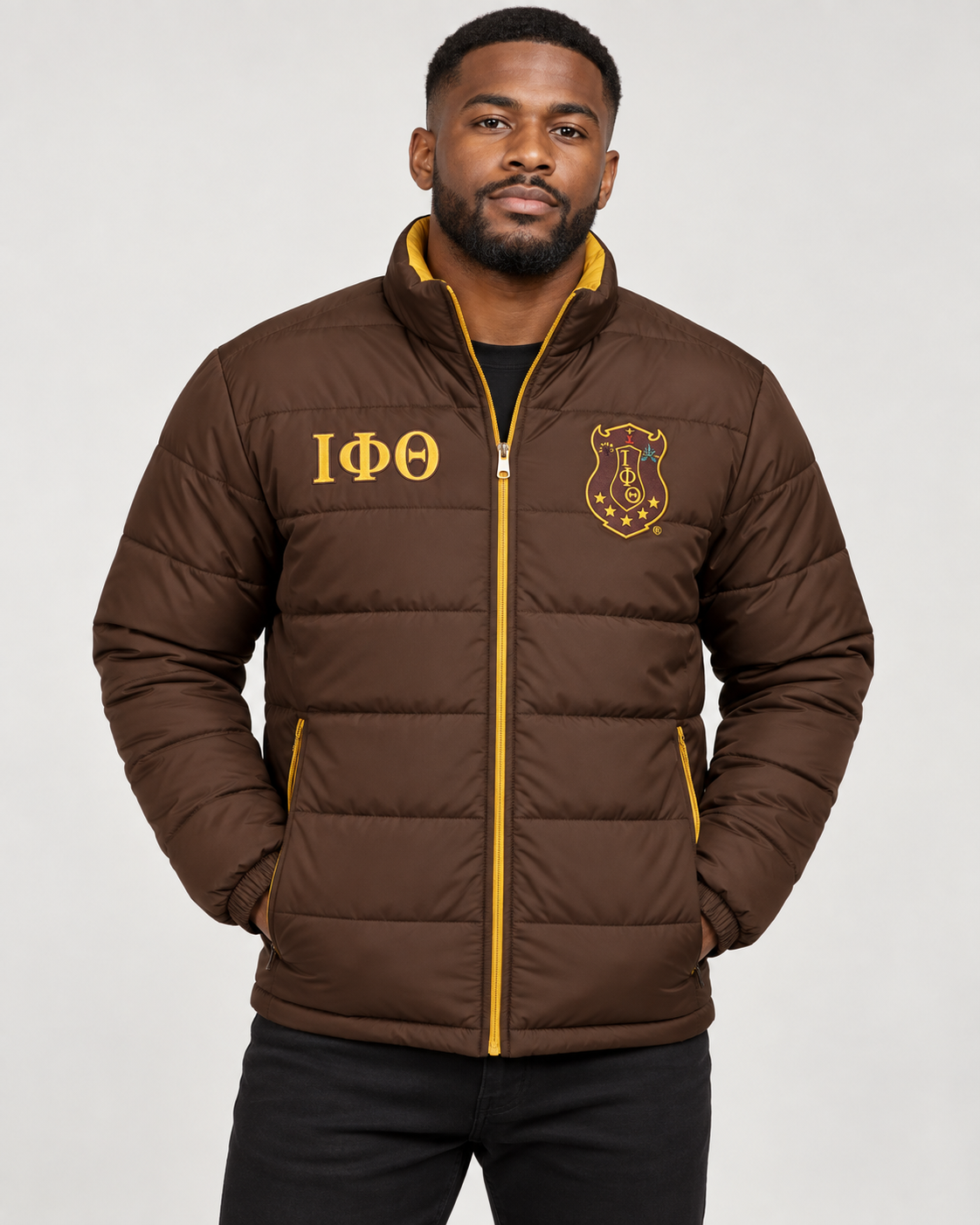 Iota Phi Theta brown puffer jacket with gold trim and custom embroidery on male model