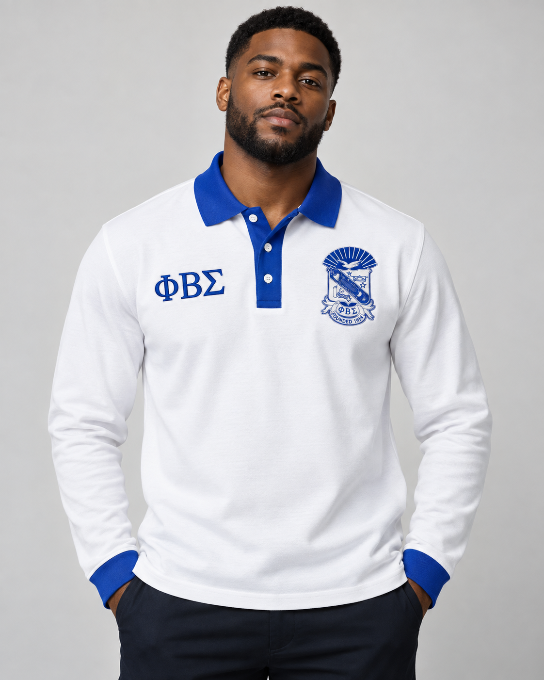 Phi Beta Sigma man wearing white long-sleeve polo with royal blue collar, placket, cuffs, crest, and Greek letters