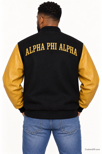 Black man modeling Alpha Phi Alpha premium contrast varsity jacket with black body and old gold sleeves, back view.