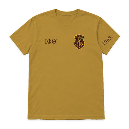 Digital product mockup: Iota Phi Theta gilded gold T-shirt with original brand-kit left-chest shield, small brown Greek letters and 1963 on wearer's left sleeve