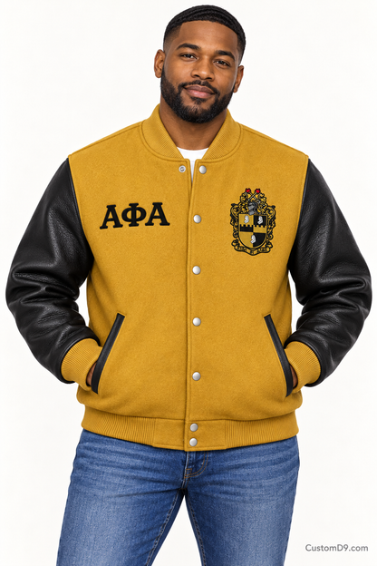 Black man modeling Alpha Phi Alpha premium contrast varsity jacket with old gold body and black sleeves, front view.