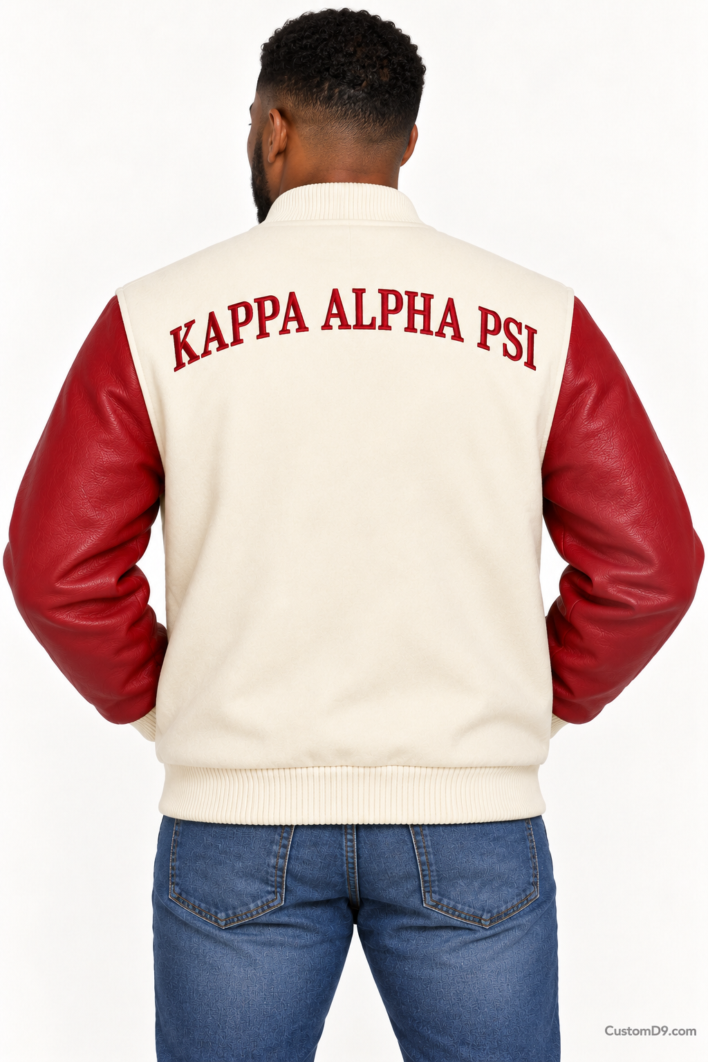 Black man modeling Kappa Alpha Psi premium contrast varsity jacket with cream body and crimson sleeves, back view.