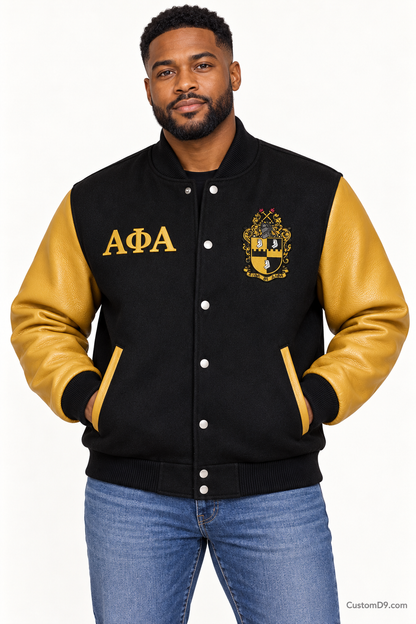 Black man modeling Alpha Phi Alpha premium contrast varsity jacket with black body and old gold sleeves, front view.