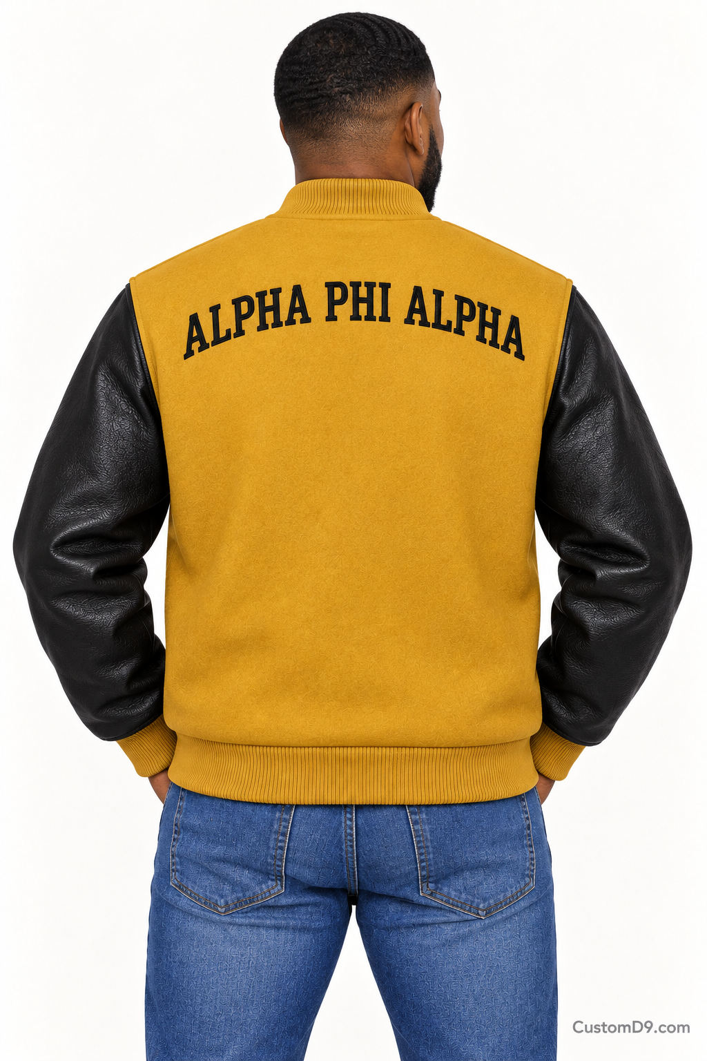 Black man modeling Alpha Phi Alpha premium contrast varsity jacket with old gold body and black sleeves, back view.