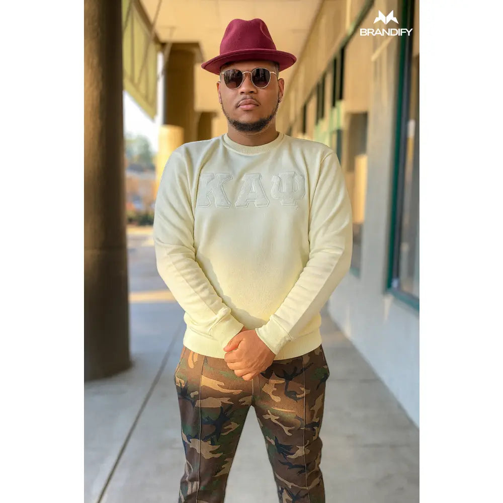 Model wearing a cream Kappa Alpha Psi sweatshirt with tonal ΚΑΨ chenille lettering